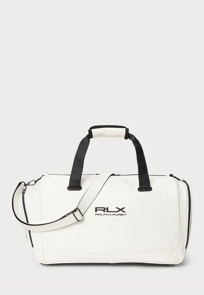 Vit duffelväska med svarta detaljer, tillverkad av slätt material. Har dubbla handtag, en avtagbar axelrem och logga på framsidan.