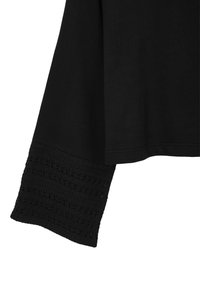 Maglione nero con un polsino in pizzo nero testurizzato. La parte principale è liscia e realizzata in un tessuto morbido, caratterizzata da linee pulite e una vestibilità comoda.