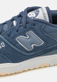 Sneaker blu in suede con upper testurizzato, chiusura con lacci e un accento bianco del logo. Suola in gomma di colore beige chiaro, per garantire aderenza.