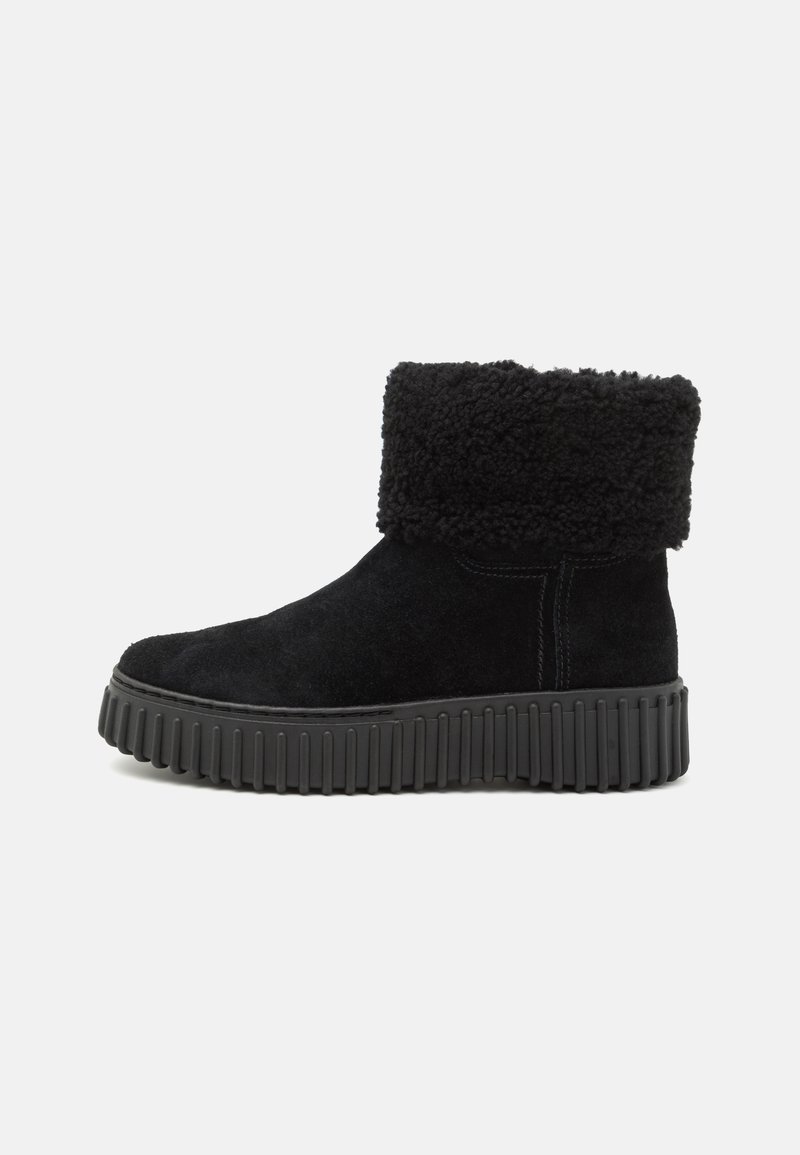 Botas de tobillo negras de ante con un puño de piel sintética y una suela de goma gruesa y acanalada. Presenta una puntera redondeada y detalles de costura mínimos.
