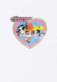 Camiseta con el logo de las Chicas Superpoderosas encima de tres personajes de dibujos animados en forma de corazón, con un diseño colorido y desgastado sobre un fondo blanco.