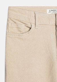 Beige kordfløyelsbukser med subtil ribbet tekstur, har en frontlomme og beltehemper. Merket leser "LINDE," som angir merke og størrelse.