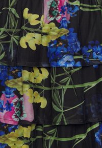 Mustakokoinen verkkokangas kirkkaalla kukkakuviolla keltaisena, vaaleanpunaisena ja sinisenä; kerroksellinen muotoilu vihreillä lehdillä ja teksturoiduilla yksityiskohdilla.