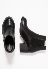 Botas negras hasta el tobillo de cuero suave con paneles laterales elásticos, un tacón grueso y una suela texturizada para mayor agarre.