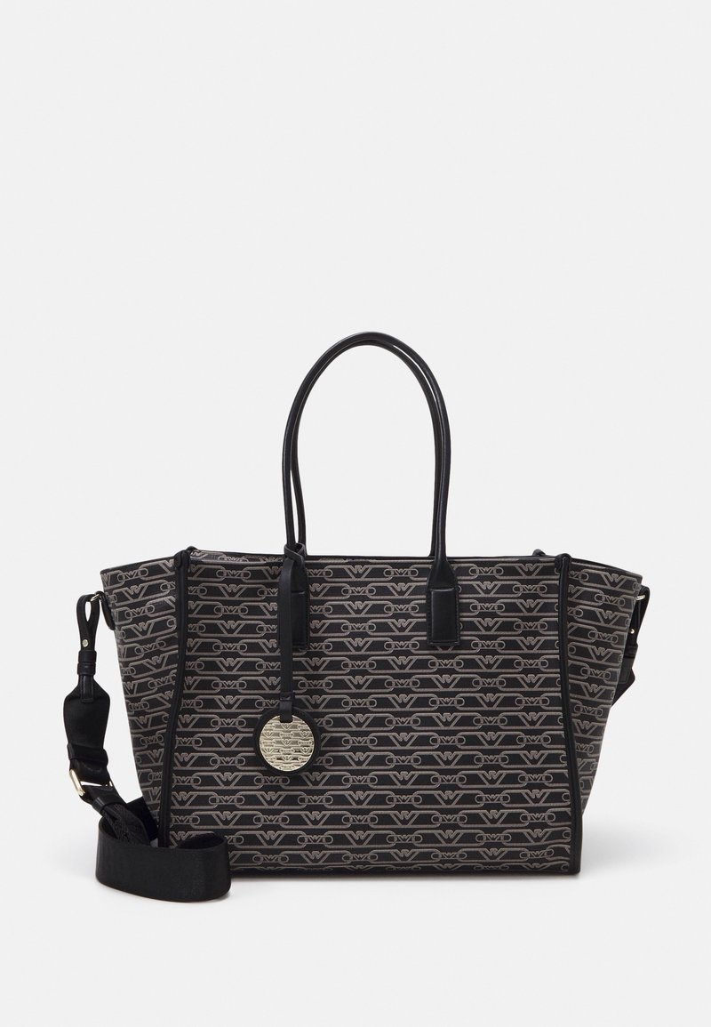 Bolso tote de patrón negro y gris con asas dobles, correa de hombro desmontable y etiqueta redonda metálica con el logo colgando de una de las asas.