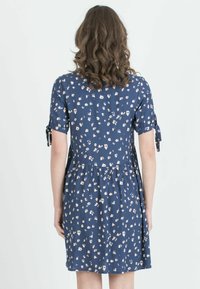 Marineblaues Blumenkleid mit kurzen Ärmeln, ausgestattet mit Bindebändern und einer gerafften Taille, aus leichtem Stoff mit einer weichen Textur.