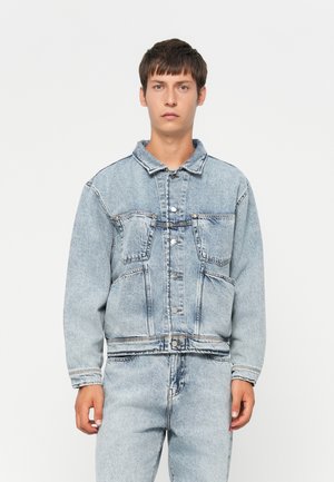 Light blue denim jacket with a collar, four front pockets, and button closure. Features a relaxed fit and visible stitching details.