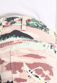 Camo-mönstrade jeans i mjuk bomullsblandning, med nyanser av rosa, grönt och svart, med rak passform och synliga fickdetaljer.