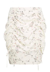 Vit rynkad minikjol med små rosa, blå och gula blommönster samt justerbara dragsnören på sidorna.