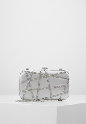 Silberne rechteckige Clutch mit geometrischen Strasssteinmustern und Kettenriemen, die auf einem weißen Podest vor einem schlichten Hintergrund liegt.