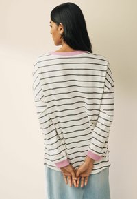 Randig långärmad topp i vitt och svart, med en rosa krage och cuffs, med en avslappnad passform och mjukt material.