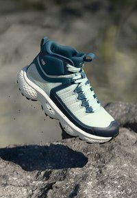 Chaussure de randonnée bleu clair avec des accents bleu foncé, tige en maille, col rembourré et semelle texturée, conçue pour la stabilité et la respirabilité.