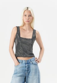 Black and white patterned fitted tank top with a square neckline and wide straps, paired with light blue high-waisted jeans.