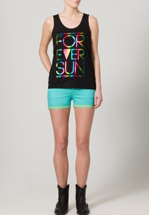 Débardeur noir avec le texte irisé "FOREVER SUN" et des motifs triangulaires. Assorti à un short teal avec une bande d'accent verte. Bottines noires.