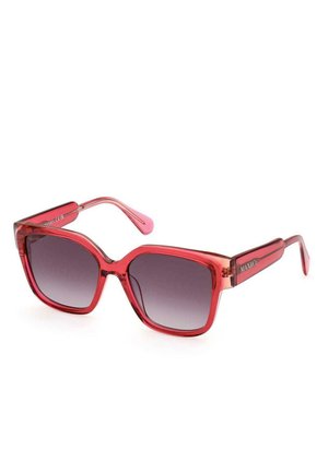 Occhiali da sole rossi traslucidi con una robusta montatura quadrata e lenti sfumate. Presentano dettagli rosa sulle tempie e un logo lateralmente.