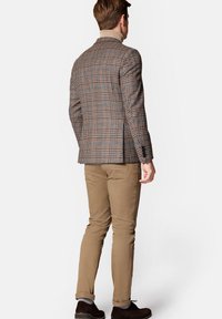 Brązowa marynarka w kratę z niebieskimi akcentami, dopasowany krój; zestawiona z beżowymi spodniami i ciemnymi butami; cechuje się teksturowanym materiałem i strukturalnym designem.