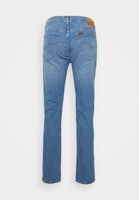 Jeans de denim azul com corte reto, apresentando uma etiqueta de couro na cintura, dois bolsos traseiros e um acabamento desbotado.