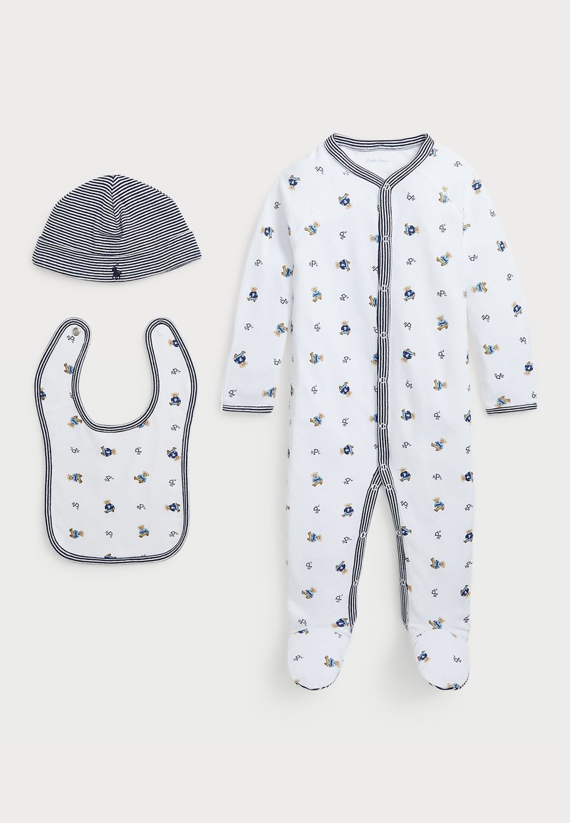 Weißes Baby-Overall mit blauen und gelben Mustern, begleitet von einem passenden gestreiften Hut und Lätzchen, alle mit einem marineblauen Rand.