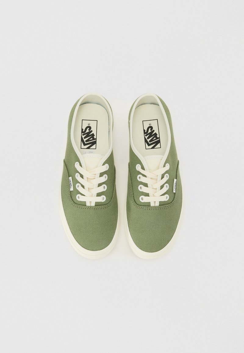 Zielone płócienne trampki z kremowymi sznurowadłami i gumowymi podeszwami. Zawierają logo Vans na języku i boku. Prosty, niski design.