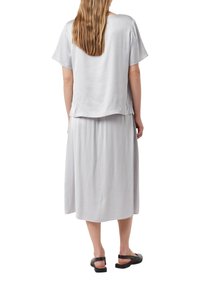 Hellgraues Zweiteiler-Outfit mit einem lockeren Kurzarmoberteil und einem schwingenden Midirock, beide aus einem glatten, weichen Stoff gefertigt.