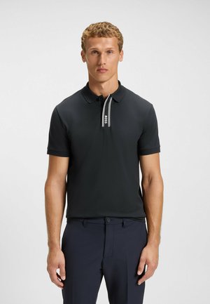 Black polo shirt with short sleeves, contrasted white striped collar, and subtle logo detail on the collar. Smooth, breathable fabric.