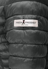 Gray puffer jacket featuring a quilted design, smooth texture, and a white label with "FRIEDA FREDDIES® NEW YORK."