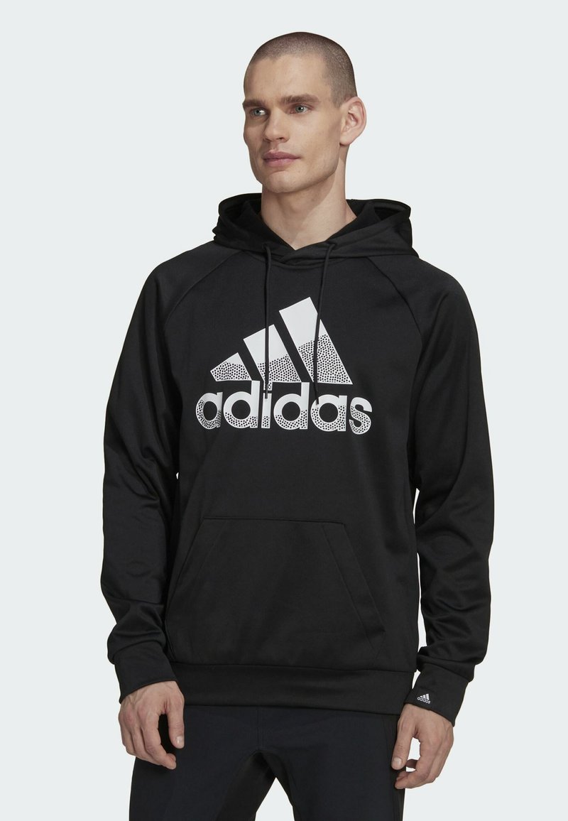 Felpa nera con cappuccio caratterizzata da un grande logo Adidas bianco con un design screziato. Ha una tasca a marsupio e un cappuccio regolabile con polsini a coste.