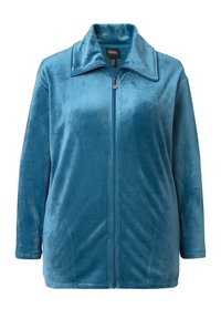 Chaqueta de cremallera en color verde azulado, fabricada en un material suave y aterciopelado; cuenta con un collar doblado y bolsillos frontales; textura lisa con un corte relajado.