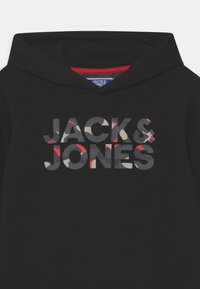 Svart huvtröja med kängurufickor och röd insida. Utrustad med en grafisk logotyp i camouflagefärger: grå, beige och röd.