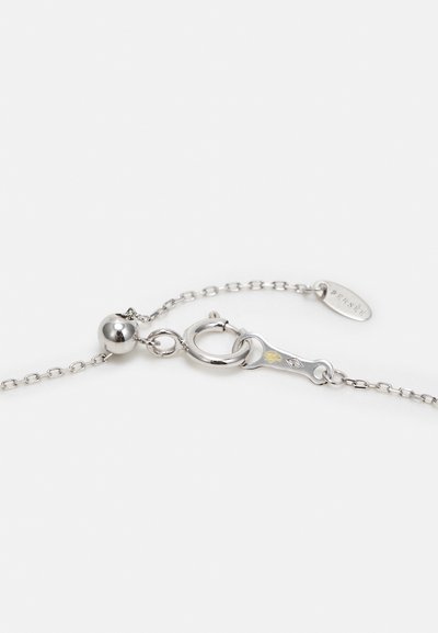 Sidabrinė grandinėlė su apvaliu sagtimi, turinti metalinį pakabuką su lapų raštu ir maža skaidraus akmens detalė.