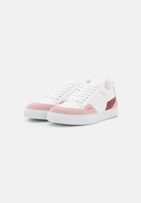 Białe skórzane sneakersy z różowymi zamszowymi akcentami i burgundowymi detalami. Gruba biała gumowa podeszwa, zaokrąglony kształt i klasyczny design na sznurówki.