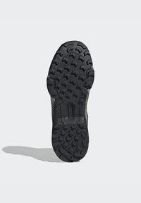 Die schwarze Außensohle besteht aus einem robusten Profil mit tiefen Rillen und sechseckigen Formen für bessere Traktion; verstärkte Kanten sorgen für Langlebigkeit.