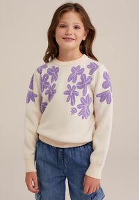 Kremni pulover s vijoličnim cvetličnim vzorcem, okroglim ovratnikom, rebrastimi manžetami in robom. Nosen s priložnostnimi denim kratkimi hlačami.