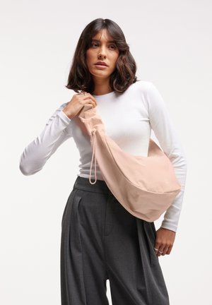 Borsa a tracolla rosa chiaro realizzata in tessuto liscio, con una parte superiore arricciata e chiusura a cordoncino, dal design arrotondato e minimalista.