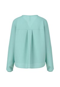 Lichtblauwe blouse met lange mouwen, gemaakt van zachte, soepele stof. Heeft een plooi-detail aan de achterkant en een afgeronde zoom met geplooide manchetten.