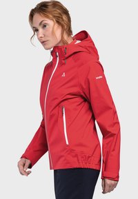 Red waterproof jacket with a hood, adjustable cuffs, white zippers, and an elasticized waist. Branded logo on the sleeve.