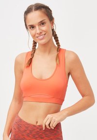 Sostenedor deportivo de color naranja brillante con escote redondeado y tirantes anchos, que presenta un diseño sin costuras y costuras en contraste para mayor detalle.