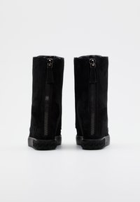 Czarne zamszowe botki za kostkę o gładkiej fakturze, z bocznym zamkiem błyskawicznym oraz gumową podeszwą z plecionym wykończeniem u podstawy.