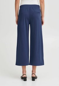 Pantalons larges de couleur marine avec une taille élastique, dotés d'une poche arrière, fabriqués dans un tissu doux et respirant pour le confort et la facilité.