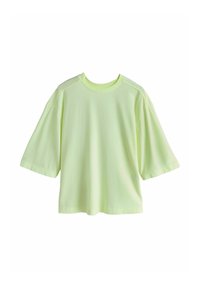 T-shirt à manches courtes coupe ample en jaune pâle avec un col rond, présenté sur un fond blanc.