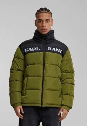 Grøn polstretjakke med en sort krave og skuldre, der har hvid "KARL KANI" branding. Teksturopfangende stof med lynlås lukning og elastiske cuffe.