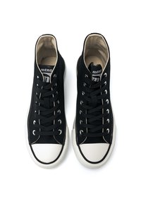 Zapatillas negras de caña alta, hechas de lona, con cordones negros, puntera de goma blanca y suela texturizada. Presenta costuras en contraste y un logo.