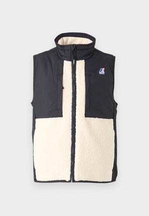 Svart utenermester vest med kremfarget fleece foran, høy krage, glidelås og logodetalj på venstre side. Lett og strukturert.