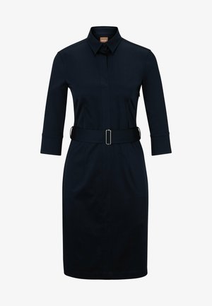 Tumedav sinine särgkleit, millel on vööpandud talje, krae ja kolmeveerandiga varrukad; sile kangas ja kohandatud lõige.