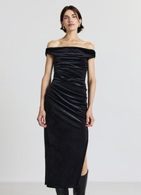 Schwarzes schulterfreies Kleid mit figurbetonter Silhouette, Raffung, seitlichem Schlitz und glattem, leicht glänzendem Stoff. Länge bis zur Mitte der Wade.