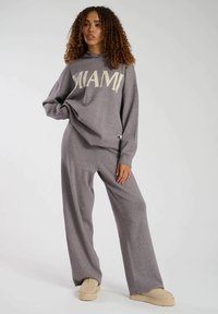 Grauer Sweater und passende Hosen im Set, mit "MIAMI" in großen cremefarbenen Buchstaben. Weicher, leichter Stoff mit lockerer Passform und weitem Bein.