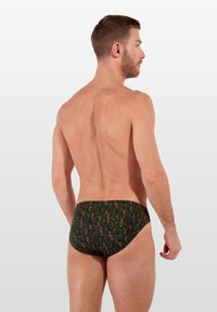 Grüne Schwimmbrüche mit einem Blattmuster in orange und roten Akzenten; aus dehnbarem Material; enganliegendes Design für Komfort und Beweglichkeit.