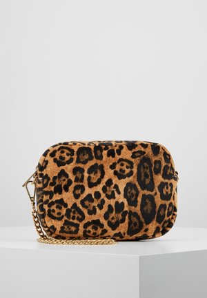 Petit sac rectangulaire imprimé léopard avec des bords arrondis et une chaîne dorée reposant sur une surface blanche contre un fond gris clair.