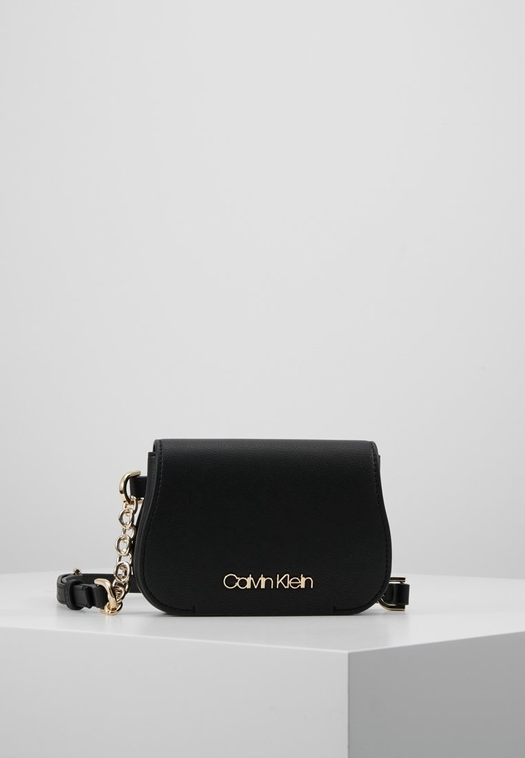 Sort syntetisk håndtaske med rund form, guldfarvede beslag, kæderem og præget logo foran.