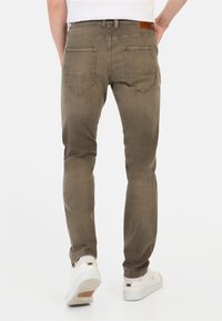 Heren slim-fit jeans in olijfgroen, gemaakt van denim met een lichte glans. Voorzien van twee achterzakken en een leren patch op de tailleband.